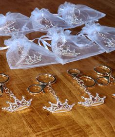 several pairs of wedding rings and tiaras on a wooden table with clear organ bags