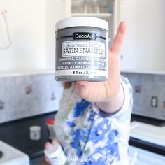 a person holding up a jar of deodorant in the kitchen with an american flag on it