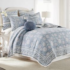 a blue and white comforter set on a bed in a room with a window