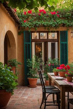 an outdoor dining area with potted flowers and greenery on the outside wall, surrounded by green shutters