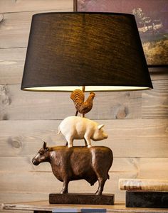 a lamp with a cow and chicken on top of it next to a book shelf