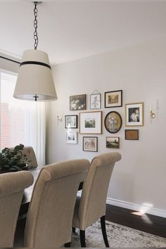 a dining room table and chairs with pictures on the wall behind it in front of a window