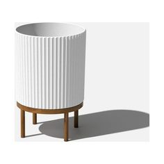 a white planter sitting on top of a wooden stand next to a white wall