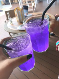 two people holding purple drinks in their hands