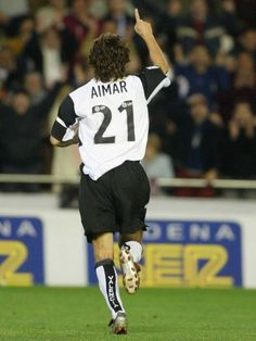 a soccer player running on the field with his arm in the air and one hand up