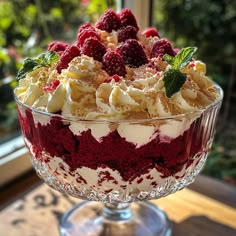 a trifle with raspberries and cream in a glass dish on a table