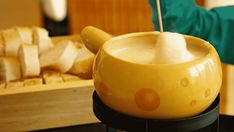 a yellow bowl sitting on top of a table next to a knife and some slices of bread