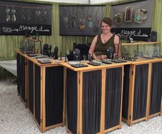 a woman standing behind a table with jewelry on it