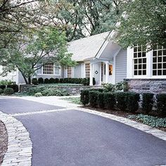 a white house with trees and bushes on the side walk next to it is an arrow pointing in opposite directions