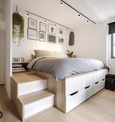 a bedroom with stairs leading up to the bed, and pictures on the wall above it