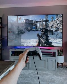 a person holding a video game controller in front of a flat screen tv