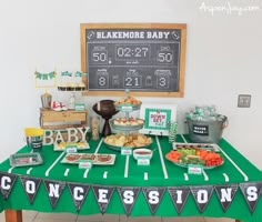 a football themed baby shower is set up on a green table with black and white pennants