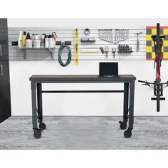 a workbench with tools hanging on the wall next to it and a bike in front of it