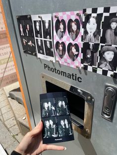 a person holding up a polaroid in front of a machine with pictures on it