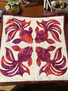 a close up of a quilt on a table with other crafting supplies in the background