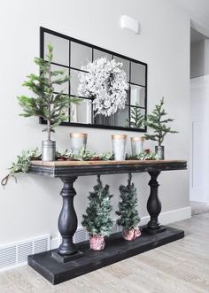 a black table topped with potted plants and greenery on top of a hard wood floor