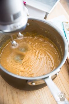 a mixing bowl filled with liquid on top of a wooden table