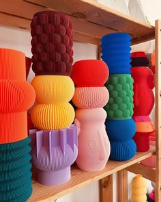 there are many different colored vases on the shelf