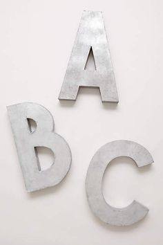 two metal letters sitting next to each other on top of a white surface with one letter missing