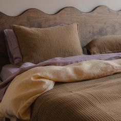 an unmade bed with brown sheets and pillows