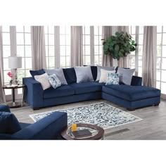 a living room with blue couches and pillows on the floor in front of large windows