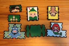 several pixel art pieces are displayed on a wooden surface, including one with an image of mario and the legend of zelda