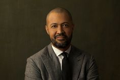 a bald man in a suit and tie posing for a photo with his arms crossed