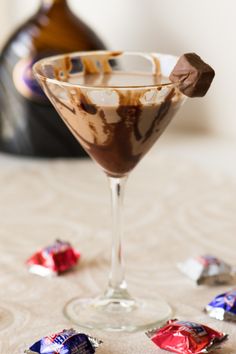 a glass filled with chocolate and candy on top of a table next to a bottle