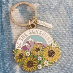 a sunflower keychain with the words be the sunshine above it and mountains in the background