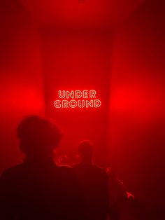 people standing in front of a red light under the word'underground'on it