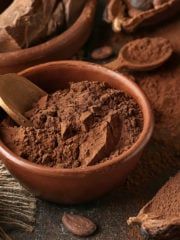 a wooden bowl filled with cocoa powder on top of a table