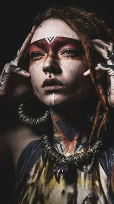 a woman with dreadlocks and tattoos on her face is posing for the camera