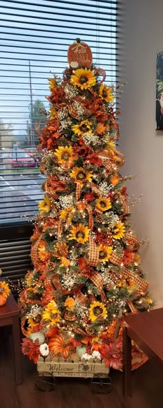 a decorated christmas tree with sunflowers and other decorations in front of a window