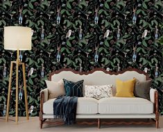 a couch sitting in front of a black wallpaper with green leaves and people on it