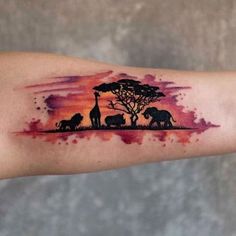 an arm tattoo with elephants and trees in the sky at sunset or dawn, on a woman's left upper arm