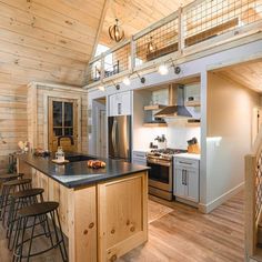 a kitchen with wooden walls and flooring next to a staircase leading up to a loft