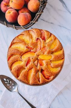 a cake with peaches on top next to a basket of peaches