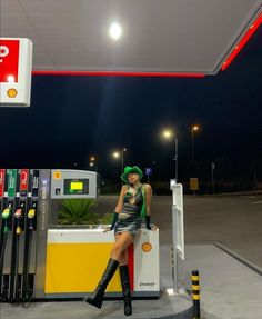 a woman sitting on top of a gas station counter next to a fuel dispenser