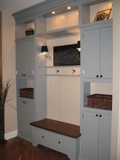 a room with some white cabinets and lights on the wall next to a wooden bench