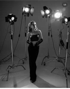 a woman is standing in front of several light stands with her hands on her hips