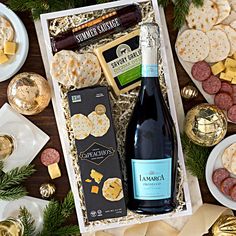 a bottle of wine, cheese and crackers in a gift box on a table