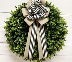 a boxwood wreath with black and white ribbon