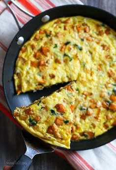 an omelet is sitting in a pan with a slice taken out of it