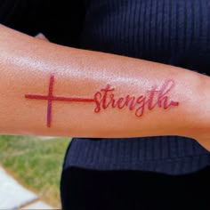 a woman's arm with the word strength on it and a cross painted on it