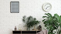 a living room with white brick walls and two plants on the side table next to it