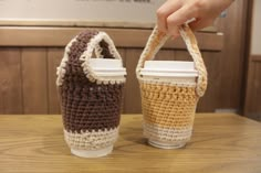 two crocheted coffee cups sitting next to each other on top of a wooden table