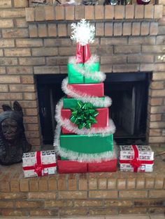 a christmas tree made out of presents sitting in front of a fire place with gifts under it