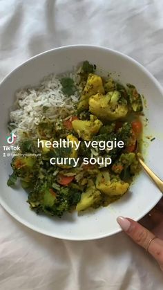 a white bowl filled with rice, broccoli and cauliflower on top of a bed