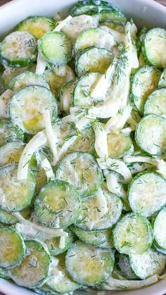 a bowl filled with cucumbers and onions on top of a wooden table