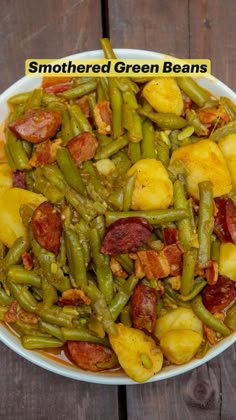 a bowl filled with green beans, potatoes and bacon on top of a wooden table